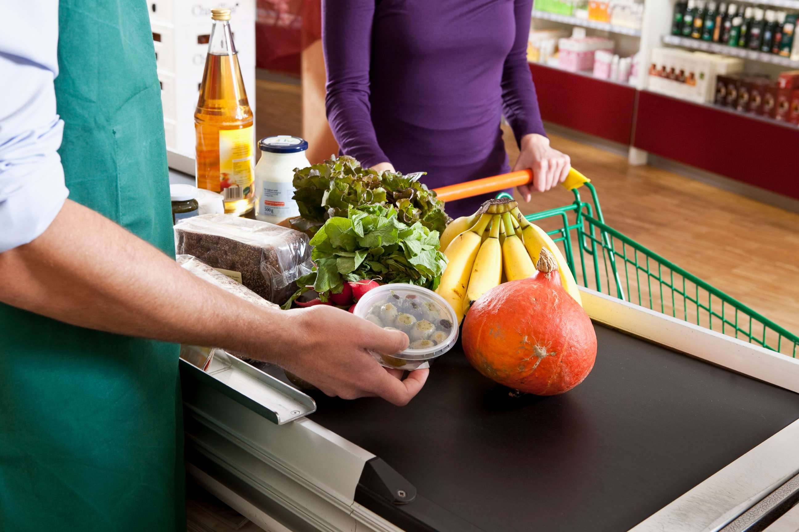 PHOTO: A cashier and customer at the checkout line of a supermarket, midsection.