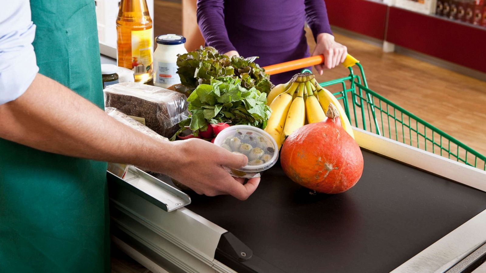 PHOTO: A cashier and customer at the checkout line of a supermarket, midsection.