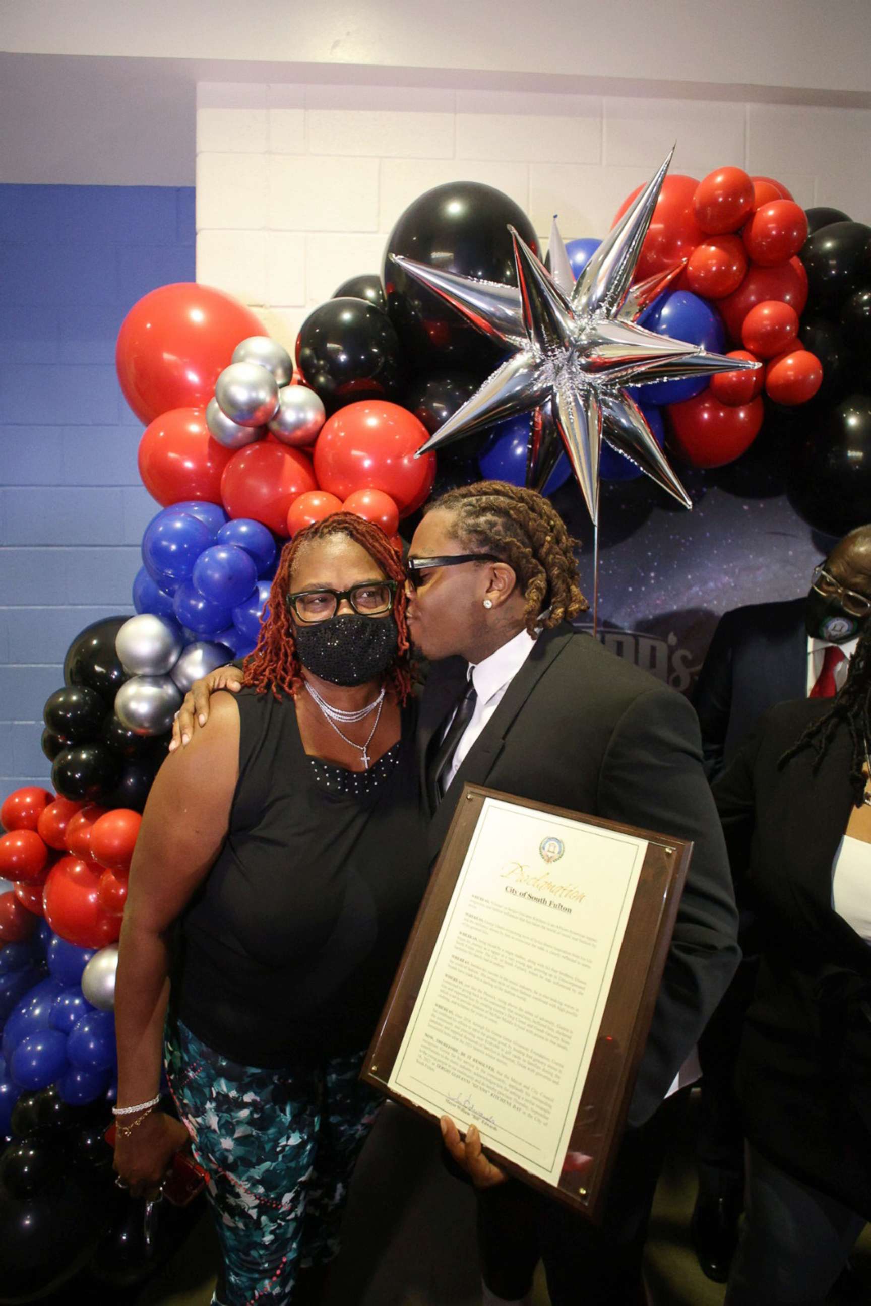 PHOTO: Hip-hop artist Gunnar kisses his mom at the grand opening of Gunna's Drip Closet and Goodr Grocery Store at McNair Middle School on Sept. 16, 2021.