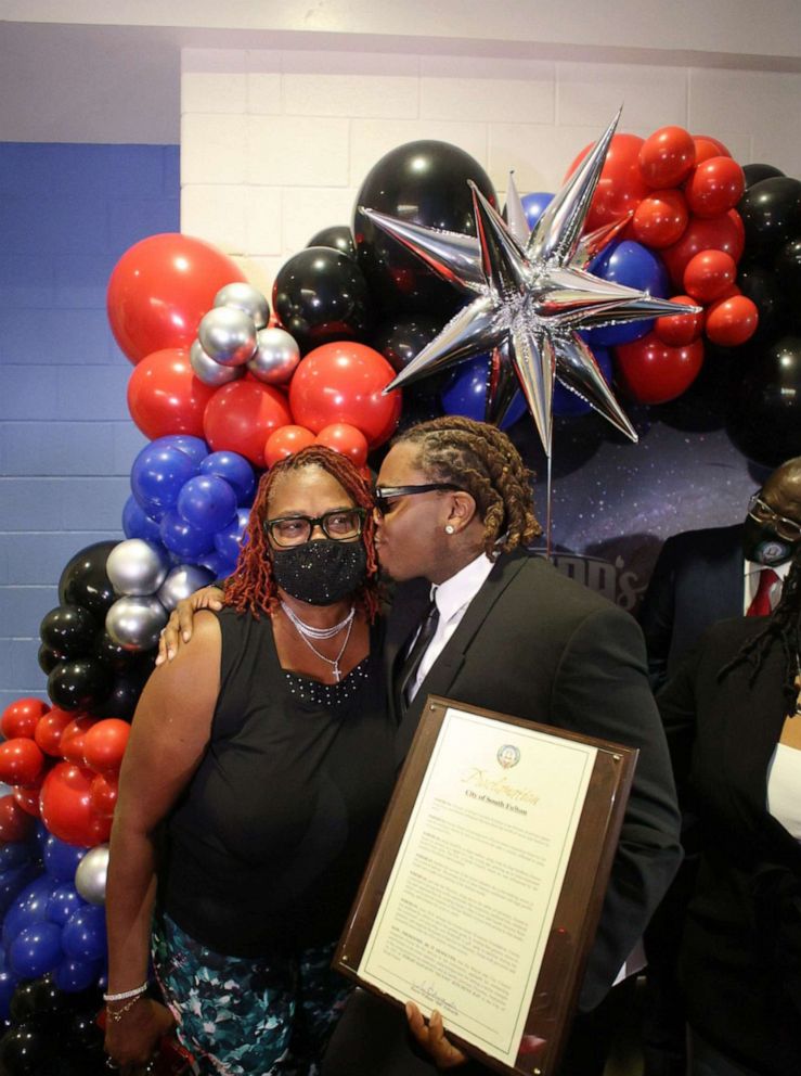 PHOTO: Hip-hop artist Gunnar kisses his mom at the grand opening of Gunna's Drip Closet and Goodr Grocery Store at McNair Middle School on Sept. 16, 2021.