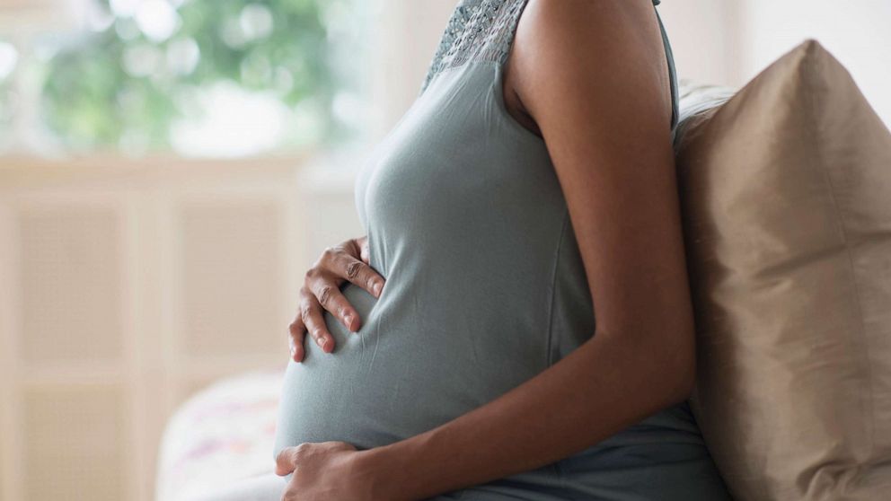 PHOTO: A pregnant woman holds her stomach at home.