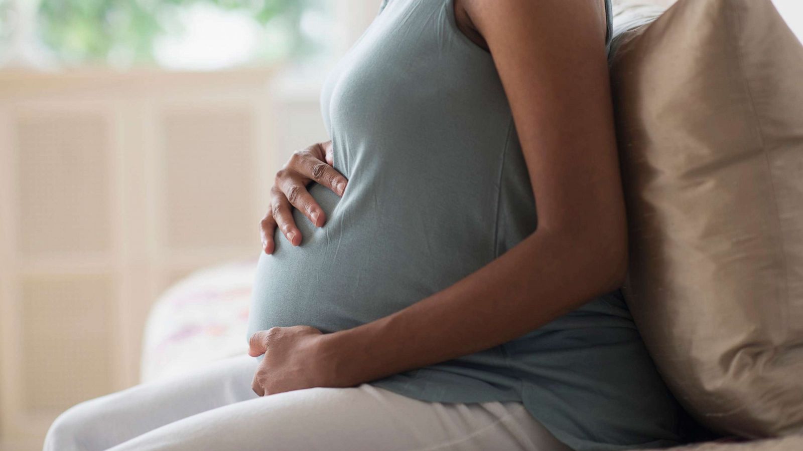 PHOTO: A pregnant woman holds her stomach at home.