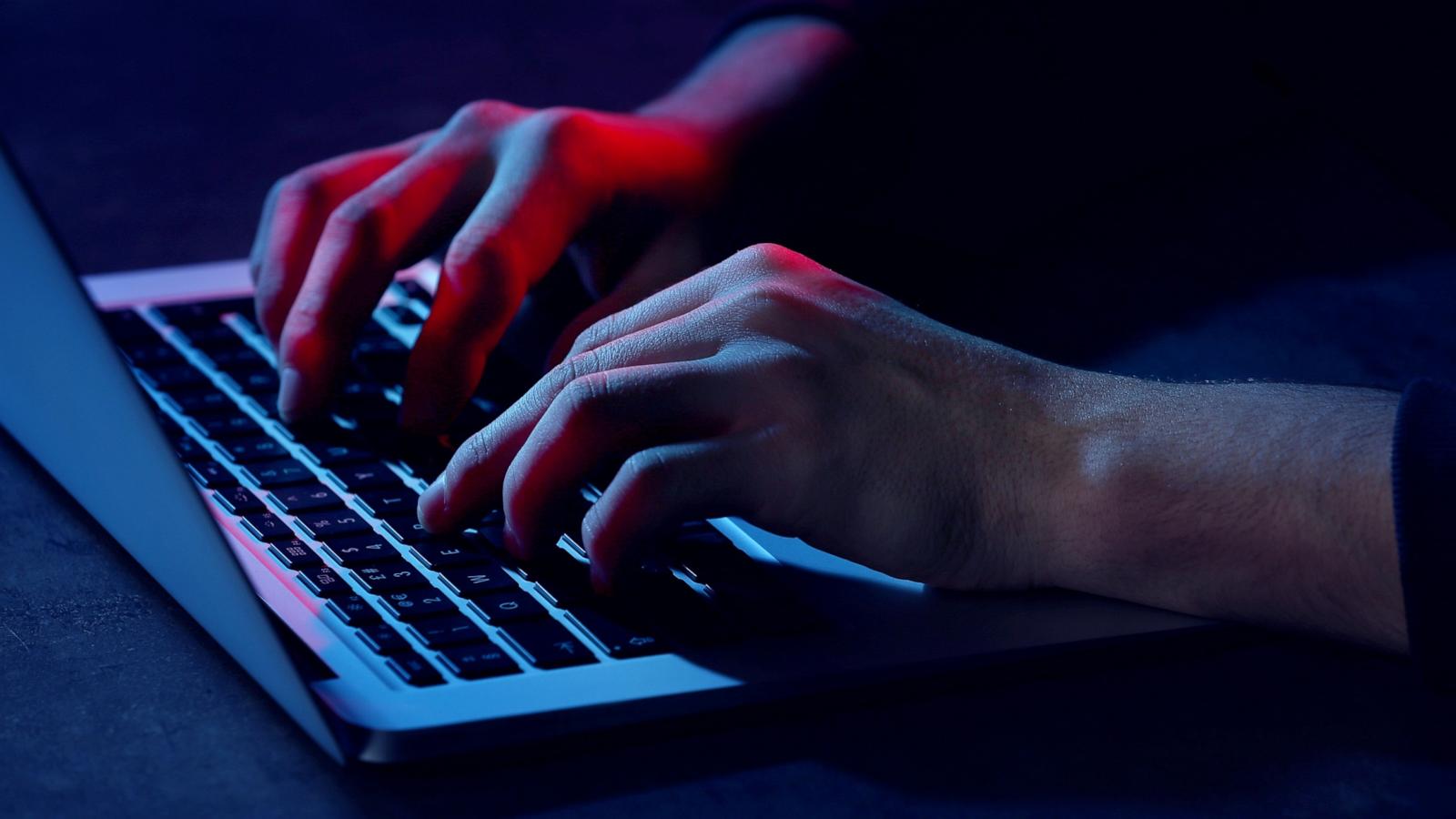PHOTO: Stock photo of a person using a computer under low light.