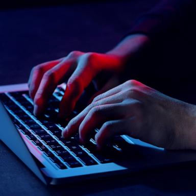 PHOTO: Stock photo of a person using a computer under low light.