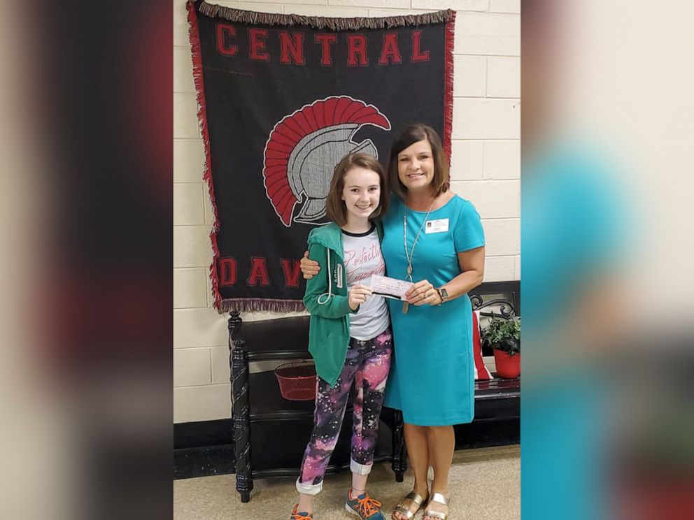 PHOTO: Hailey Hager, 14, presents a check to pay off student lunch debt to a school official in Lexington, North Carolina.