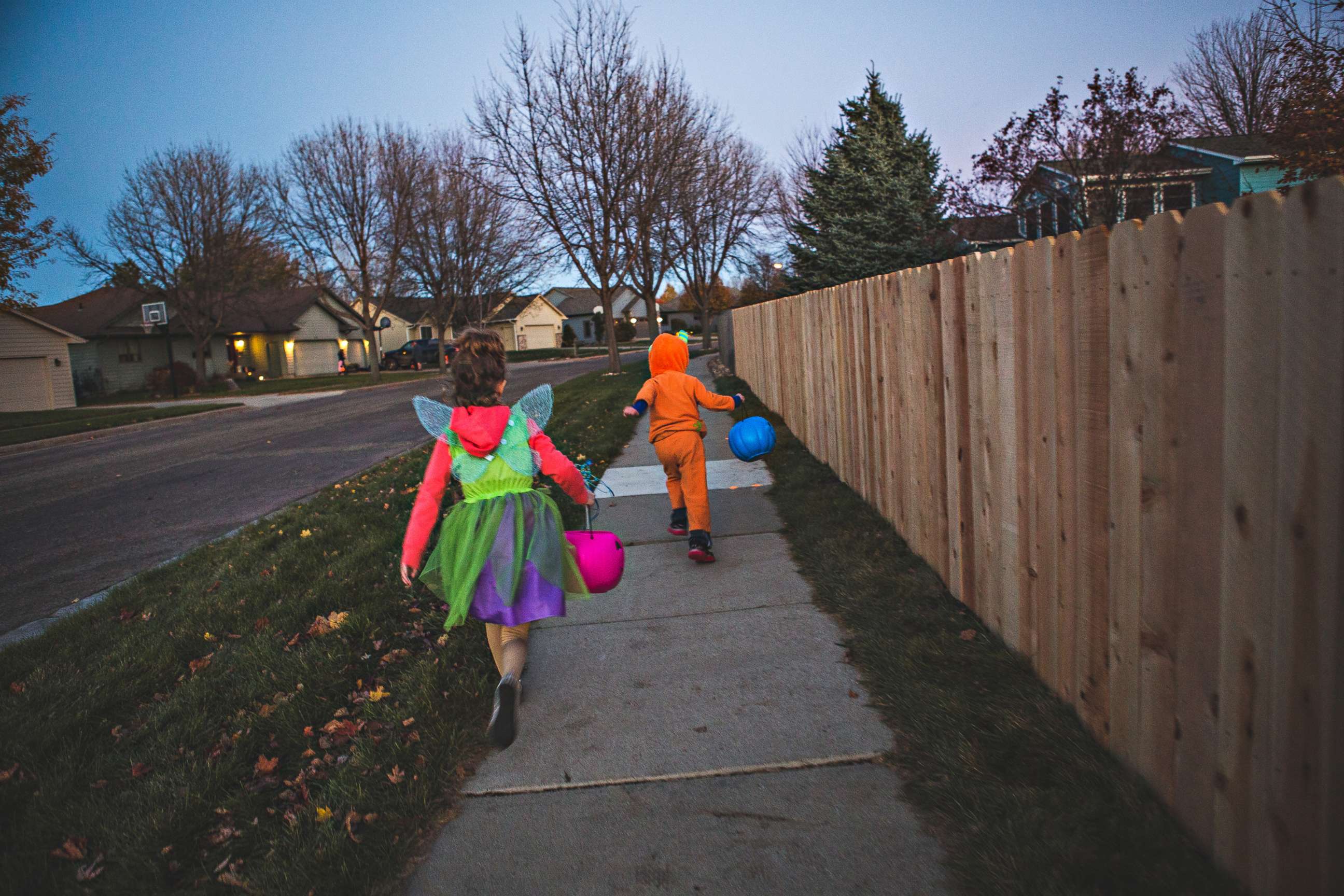 PHOTO: Costumed children run down a sidewalk on Halloween. 
