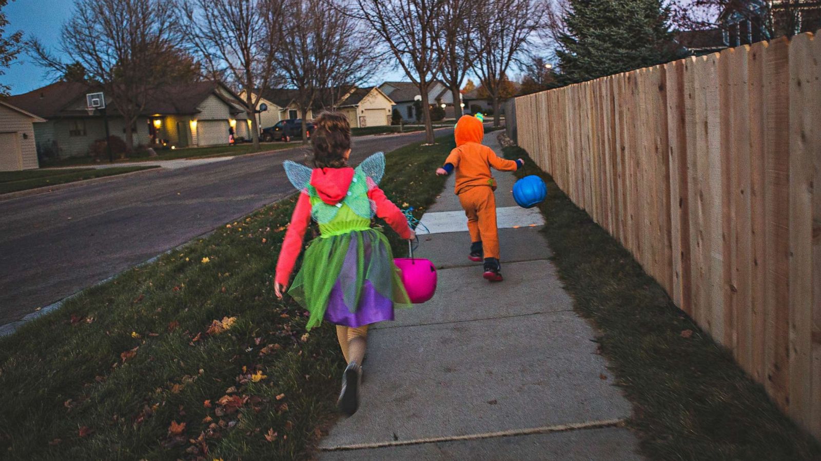 PHOTO: Costumed children run down a sidewalk on Halloween.