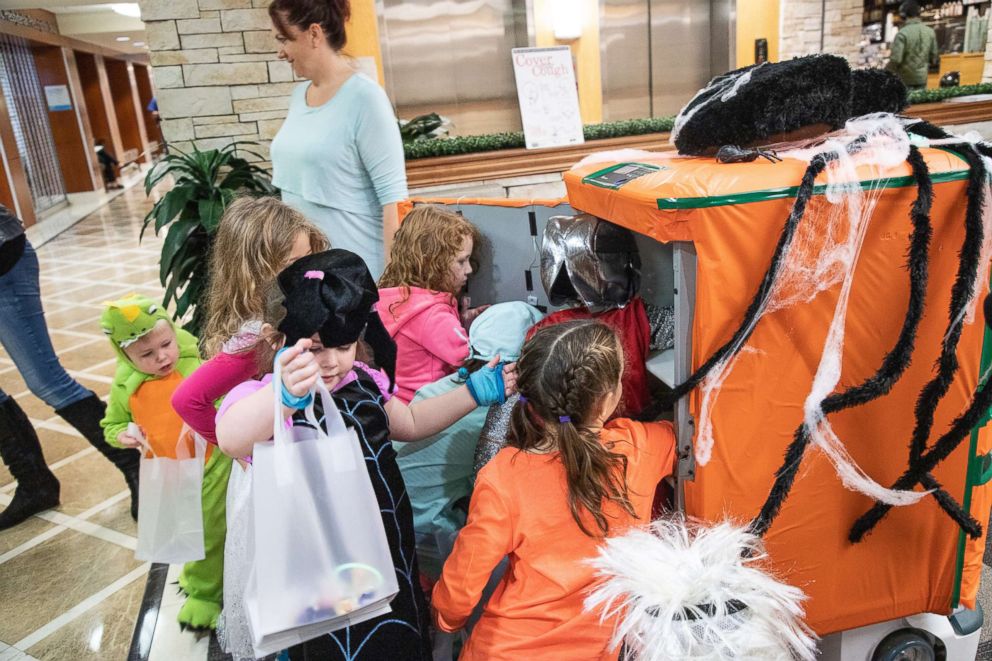 PHOTO: Children in costumes take candy from a TUG robot decorated as a jack-o'-lantern during a Halloween event at UPMC Presbyterian hospital in Pittsburgh, Oct. 26, 2018.