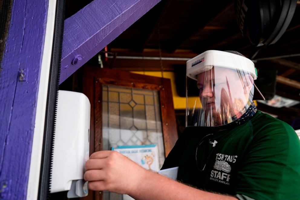 PHOTO: A restaurant employee installs a hand sanitizer dispenser as the restaurant prepares to open during the Coronavirus pandemic at Fish Tails bar and grill on May 29, 2020, in Ocean City, Md.