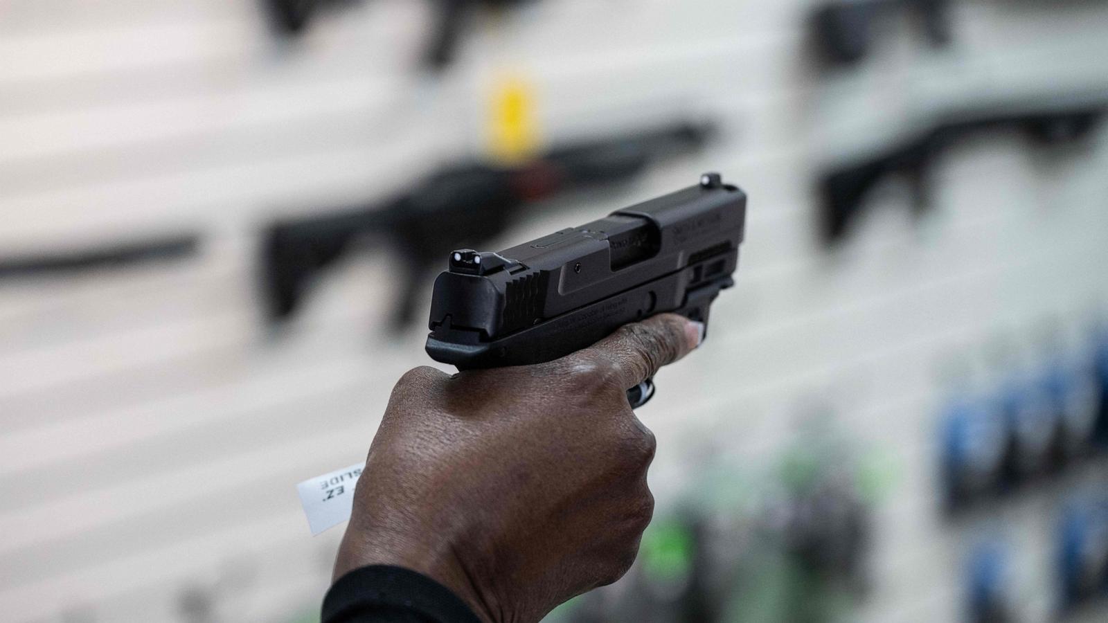 PHOTO: Fay Brake co-owner of EJB's Gun Shop shows a pistol to customers at the store in Capitol Heights, Maryland, March 14, 2023.