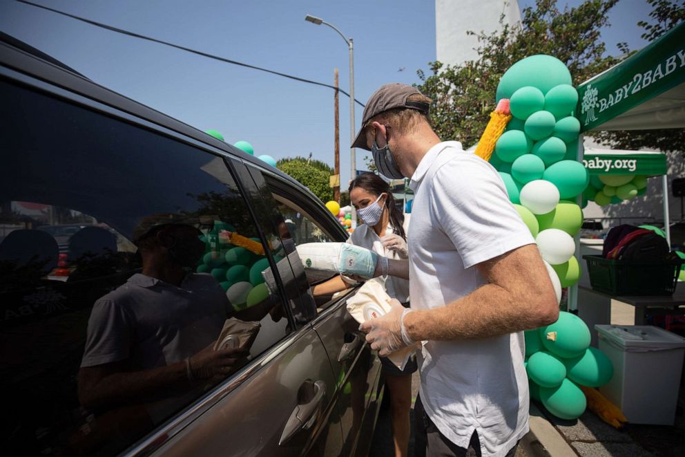 PHOTO: Prince Harry and Meghan hand out supplies to families at a Baby2Baby drive-through event at Dr. Owen Lloyd Knox Elementary School in South Los Angeles.