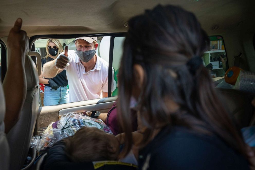 PHOTO: Prince Harry and Meghan hand out supplies to families at a Baby2Baby drive-through event at Dr. Owen Lloyd Knox Elementary School in South Los Angeles.