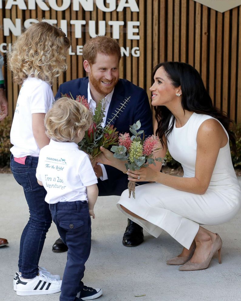 PHOTO: Prince Harry, Duke of Sussex and Meghan, Duchess of Sussex are presented with native flowers from children, Dasha Gallagher and Finley Blue, during a ceremony at Taronga Zoo, Oct. 16, 2018, in Sydney.