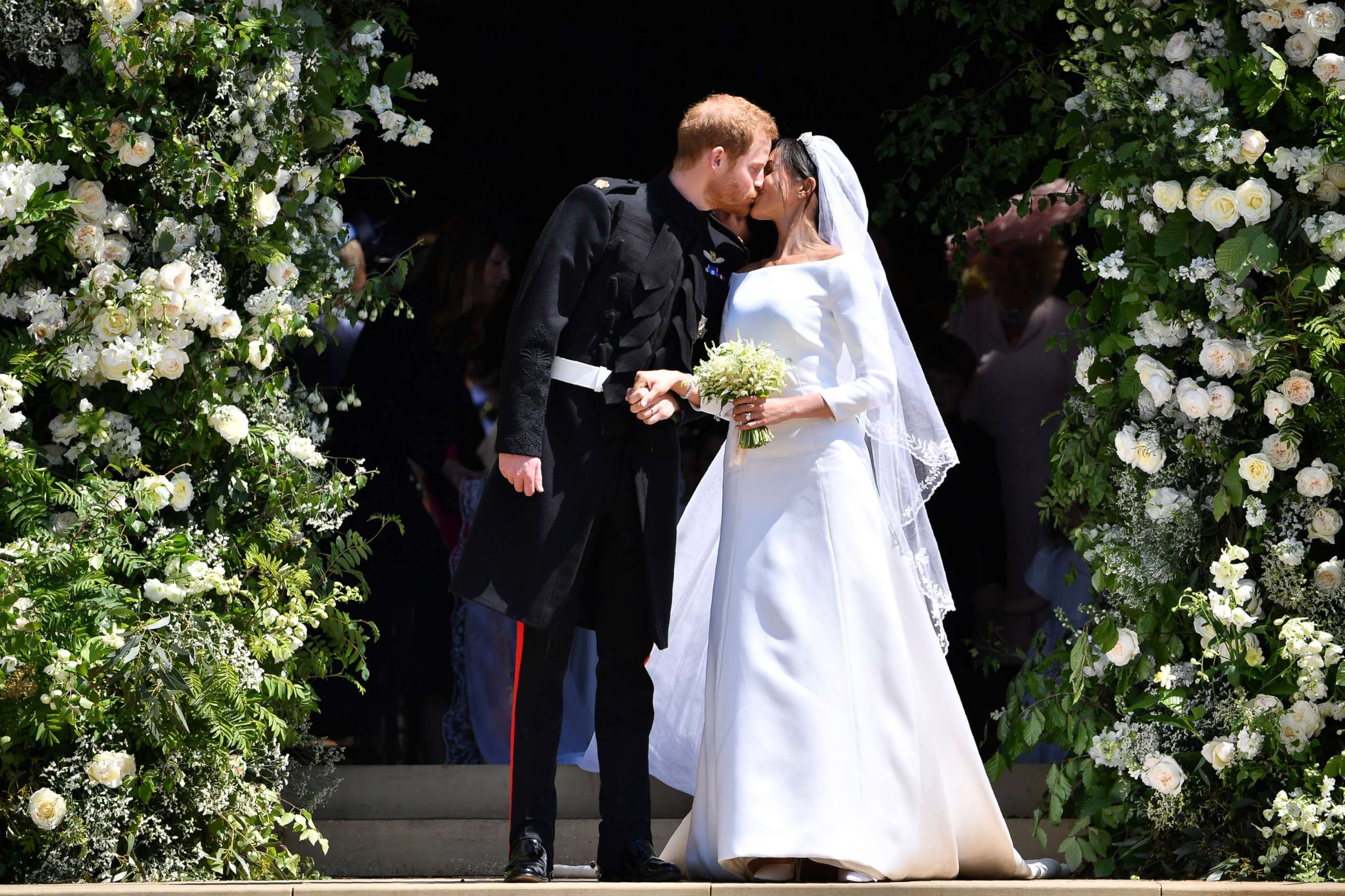 PHOTO: Britain's Prince Harry, Duke of Sussex kisses his wife Meghan, Duchess of Sussex as they leave from the West Door of St George's Chapel, Windsor Castle on May 19, 2018, in Windsor England.