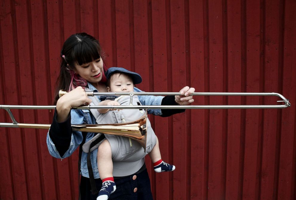 PHOTO: Haruka Kikuchi holds a sliding trombone and her 9-month-old son Shouta.