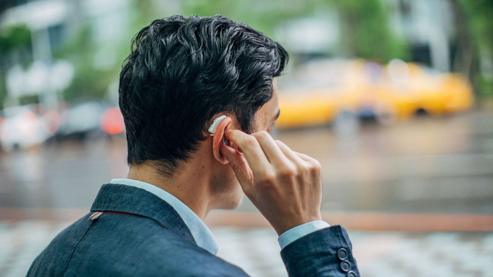 PHOTO: In an undated stock photo, a young person in a suit is seen wearing a hearing aid on a city street.