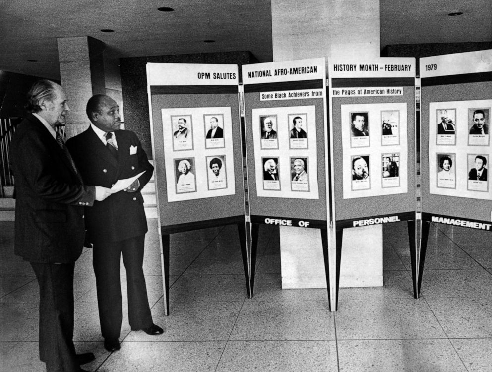 PHOTO: Alan K Campbell and. Dr J Rupert Picott stand next to a Black History Month exhibit in Washington, DC, 1976.