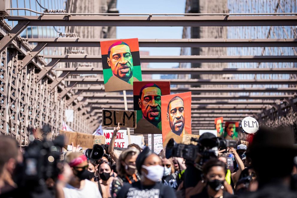 PHOTO: Thousands of protesters walk in a peaceful protest across the Brooklyn Bridge holding signs that read, "BLM" and three painted portraits of George Floyd with the Brooklyn Bridge Arch in the background.