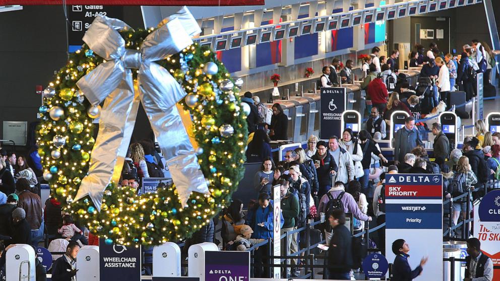 PHOTO: A holiday wreath hangs from the ceiling as travelers line up to enter the security checkpoint in Terminal A at Logan Airport as others wait at the ticket counter, Dec. 14, 2023.