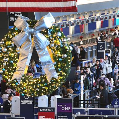 PHOTO: A holiday wreath hangs from the ceiling as travelers line up to enter the security checkpoint in Terminal A at Logan Airport as others wait at the ticket counter, Dec. 14, 2023.