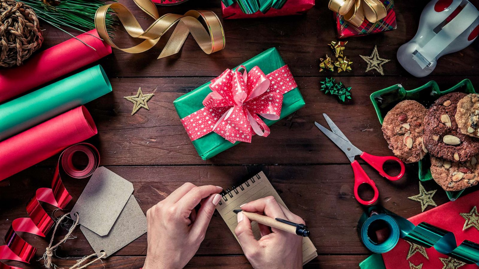 PHOTO: A woman makes a list on note pad while wrapping holiday gifts.