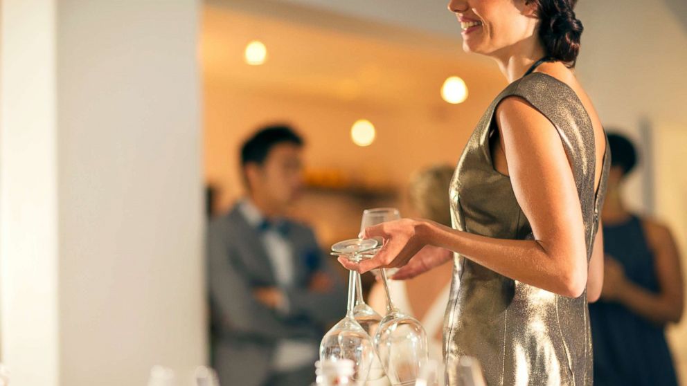 PHOTO: This stock photo depicts a woman at a party holding wine glasses.