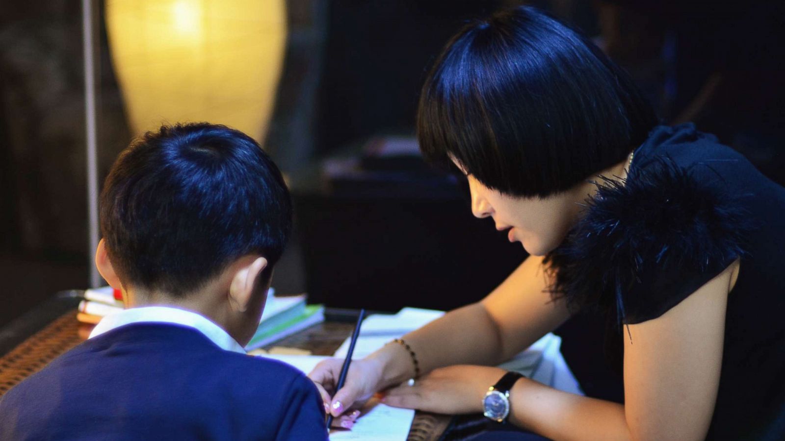 PHOTO: Mother helping her son with his homework after work.