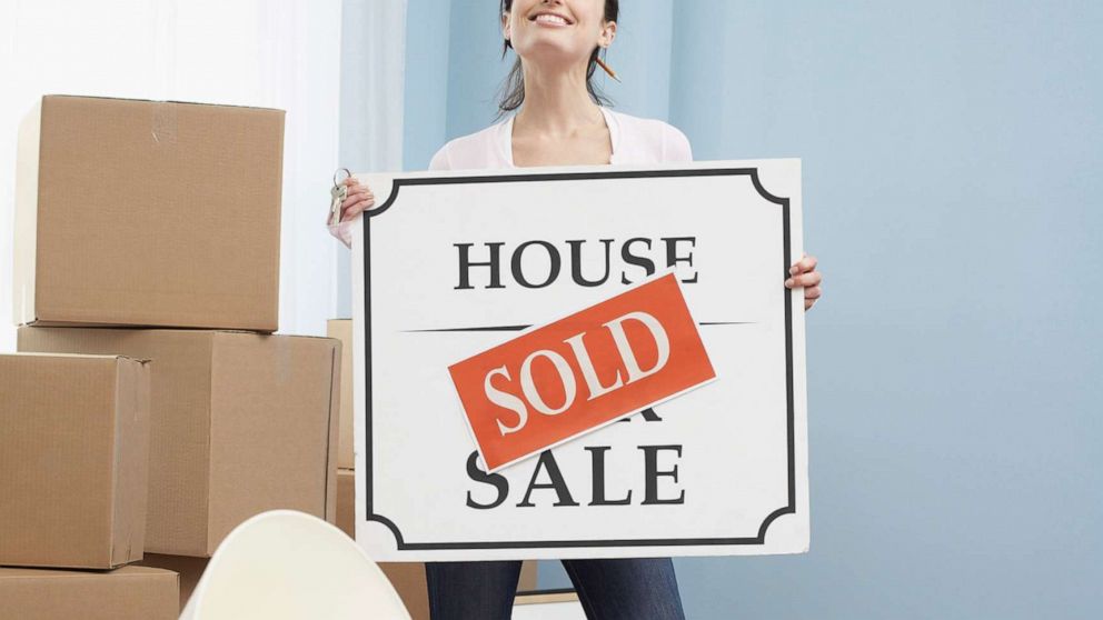 PHOTO: An undated stock photo depicts a woman holding a "sold" sign in a new home.
