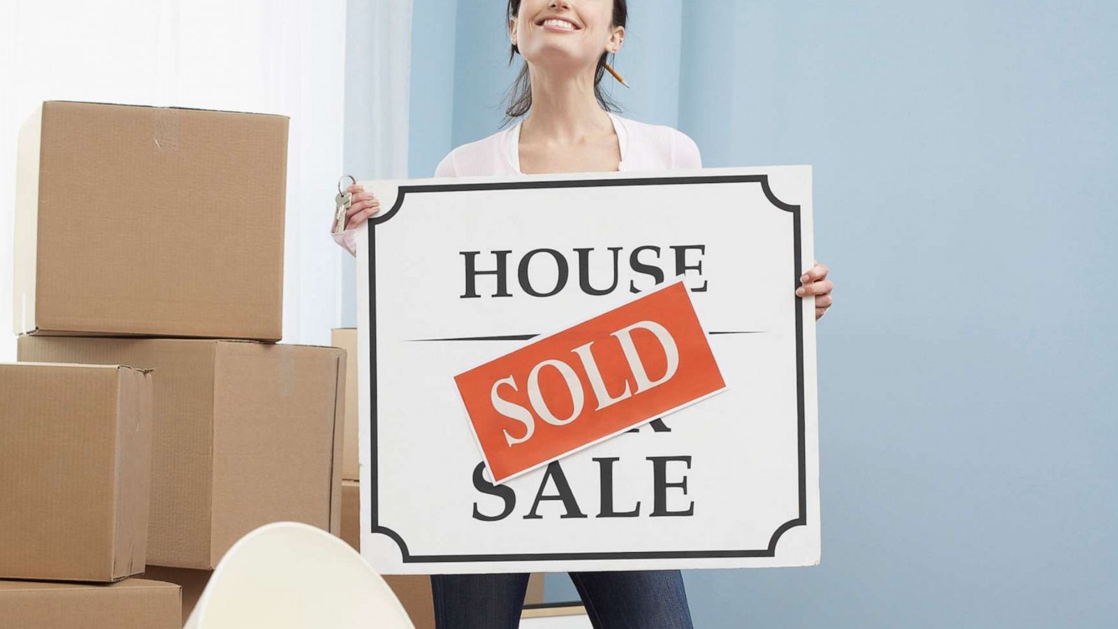 PHOTO: An undated stock photo depicts a woman holding a "sold" sign in a new home.