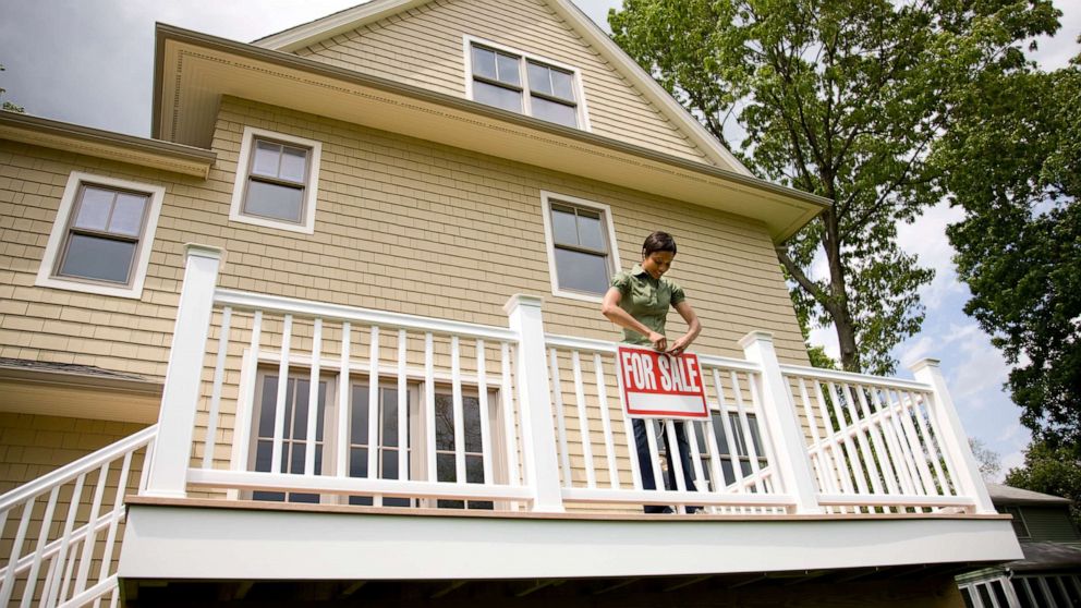PHOTO: An undated stock photo depicts a woman holding a "for sale" sign on a new home.