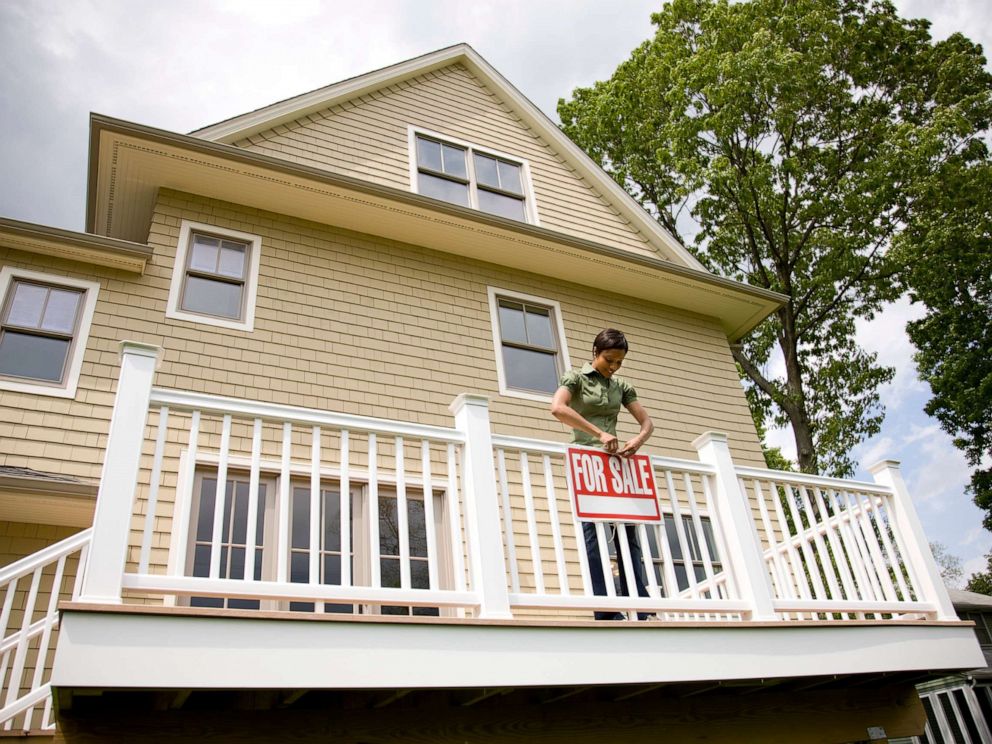 PHOTO: An undated stock photo depicts a woman holding a for sale sign on a new home.