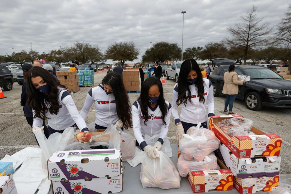 PHOTO: Houston Texans cheerleaders pack bags of peaches during the Houston Food Bank food distribution at NRG Stadium, Feb. 21, 2021, in Houston, Texas.