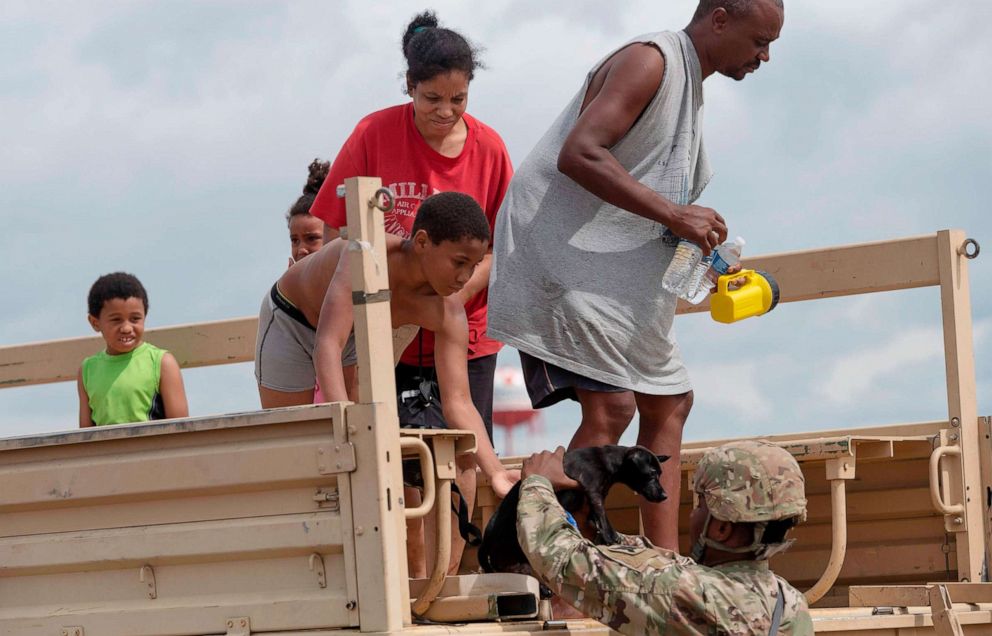 PHOTO: Members of the National Guard help a family off a truck after they were evacuated from their home, following the passing of Hurricane Laura in Lake Charles, La., Aug. 27, 2020.