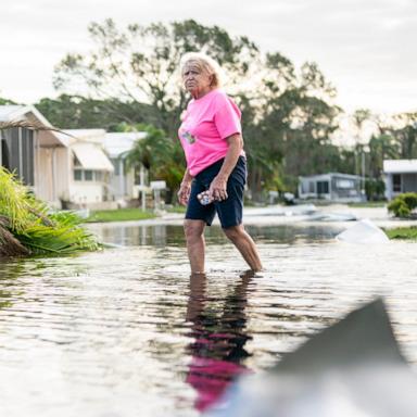 PHOTO: A woman walks along a flooded street in the aftermath of Hurricane Milton, Oct. 10, 2024, in Osprey, Fla.