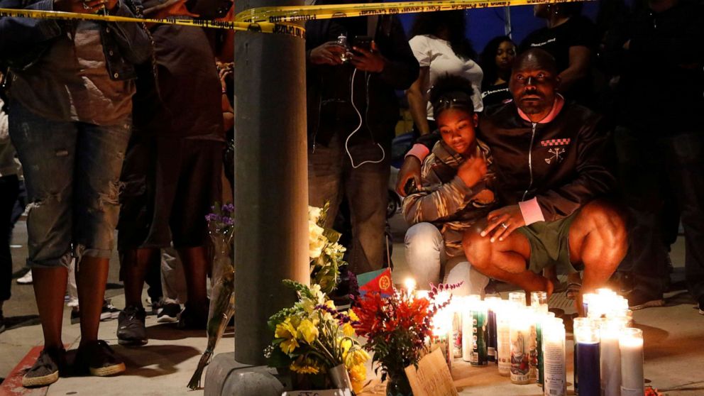 PHOTO: Haitian-French actor Jimmy Jean-Louis and his daughter Jasmin, 16, gather around candles set up across from the clothing store of rapper Nipsey Hussle in Los Angeles, March 31, 2019.