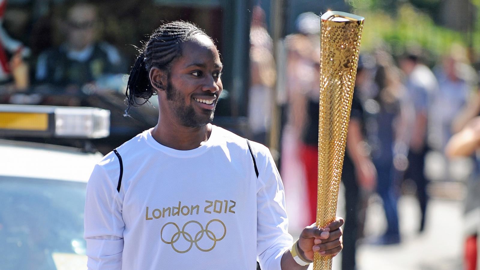 PHOTO: In this July 23, 2012, file photo, torchbearer Jason Arday carries the Olympic Flame on the Torch Relay leg between Sutton and Merton, in London.