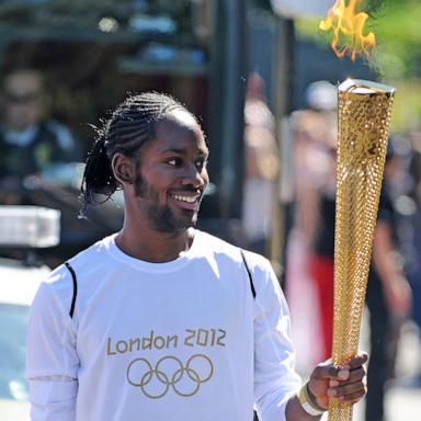 PHOTO: In this July 23, 2012, file photo, torchbearer Jason Arday carries the Olympic Flame on the Torch Relay leg between Sutton and Merton, in London.