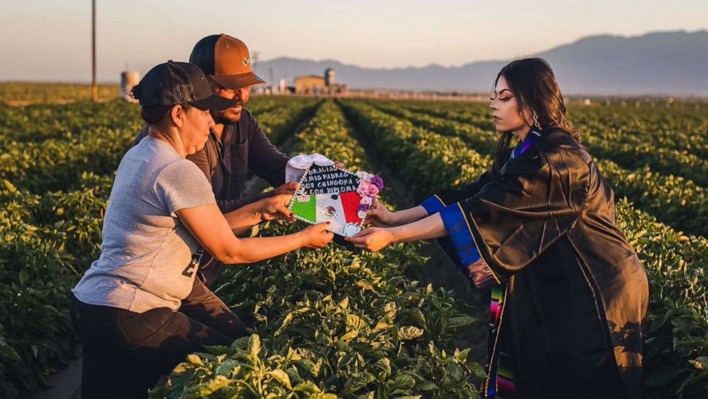 PHOTO: Jennifer Rocha, 21, a new graduate from the University of California San Diego, poses for a graduation photo with her parents in the fields where they worked to support her education.