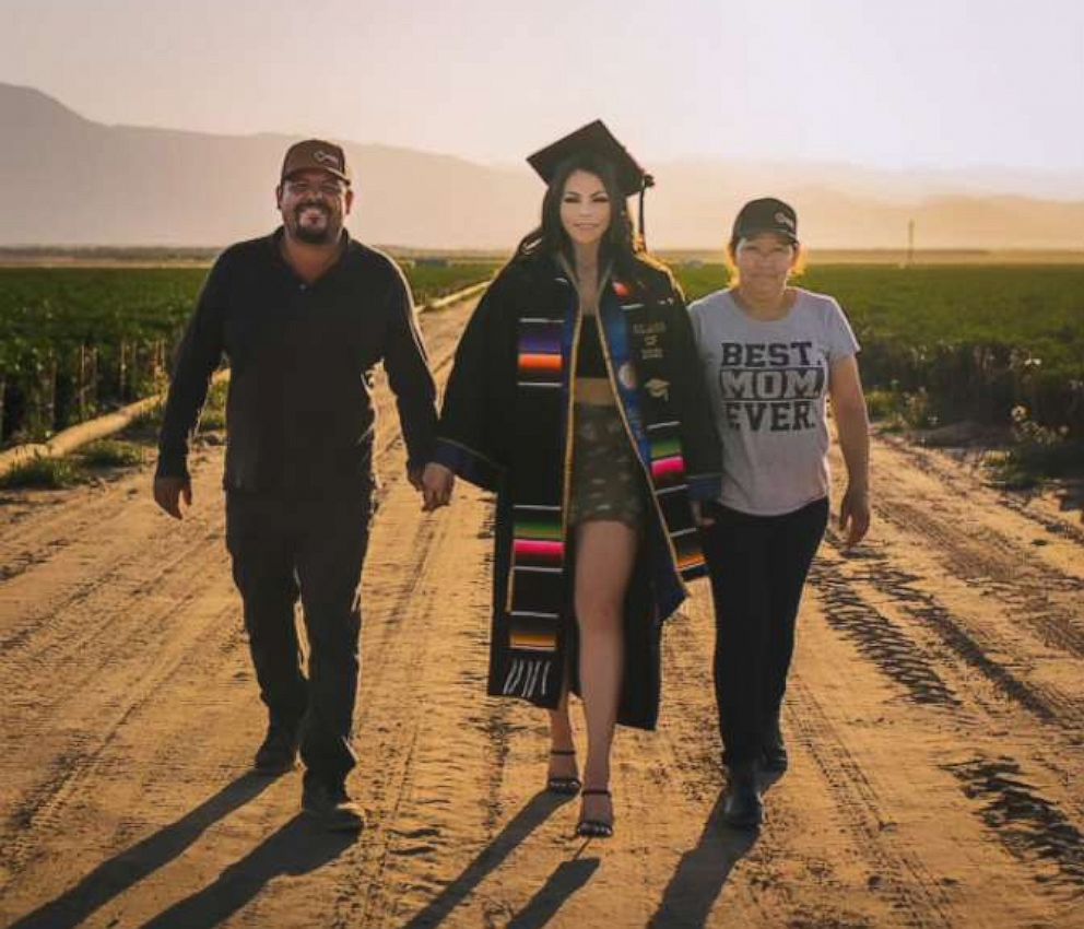 PHOTO: Jennifer Rocha, 21, a new graduate from the University of California San Diego, poses for a graduation photo with her parents in the fields where they worked to support her education.
