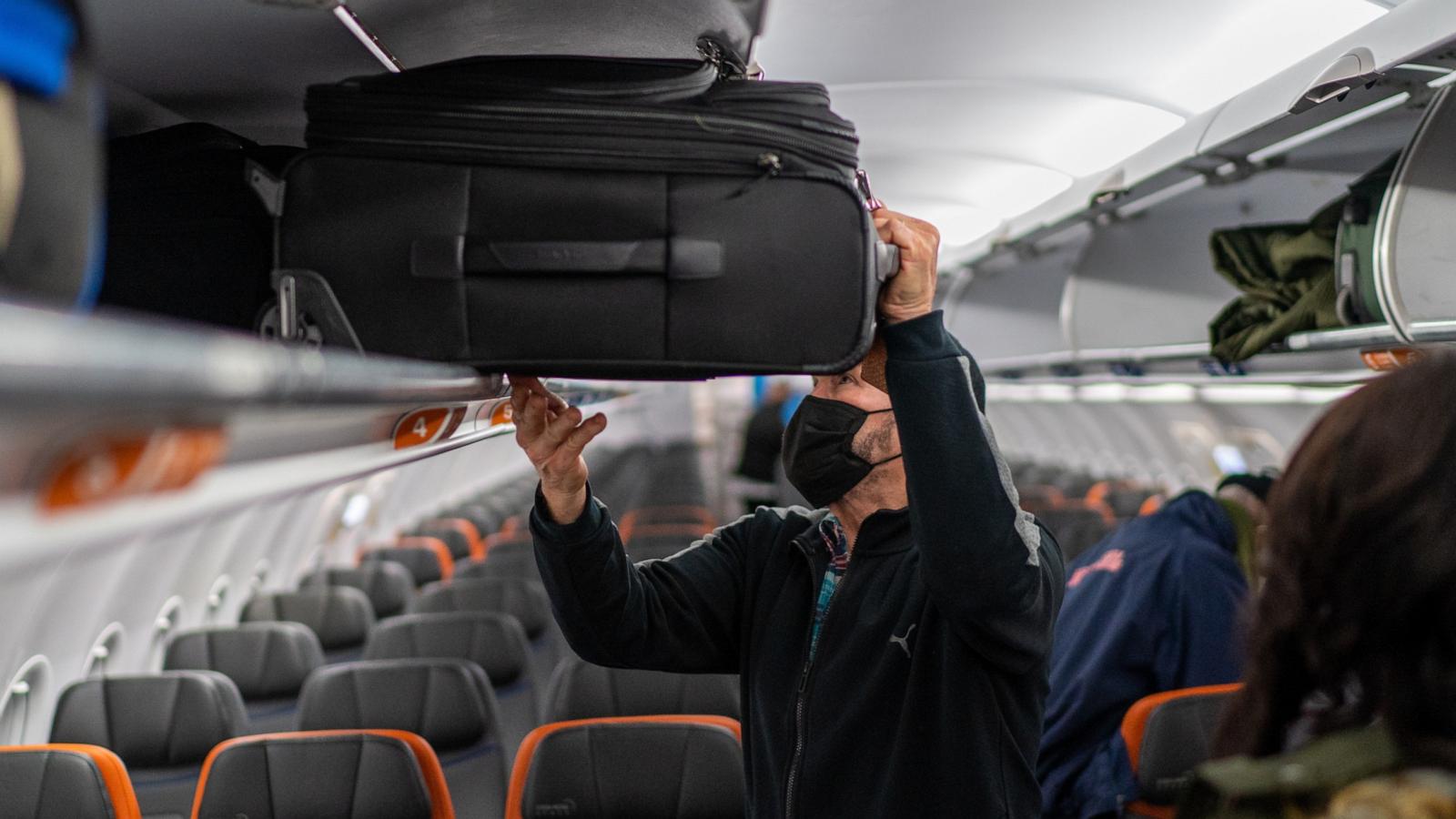 PHOTO: A JetBlue passenger puts his carry-on luggage into an overhead compartment January 28, 2022 at John F. Kennedy International Airport in New York City.