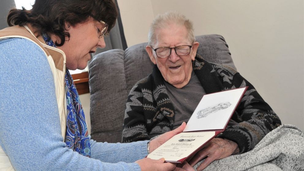 PHOTO: John Quinlan Jr. is presented with his high school diploma by Weymouth School Committee member, Kathy Sullivan Curran on his 99th birthday in his home in Weymouth, Mass., Feb 17, 2020.