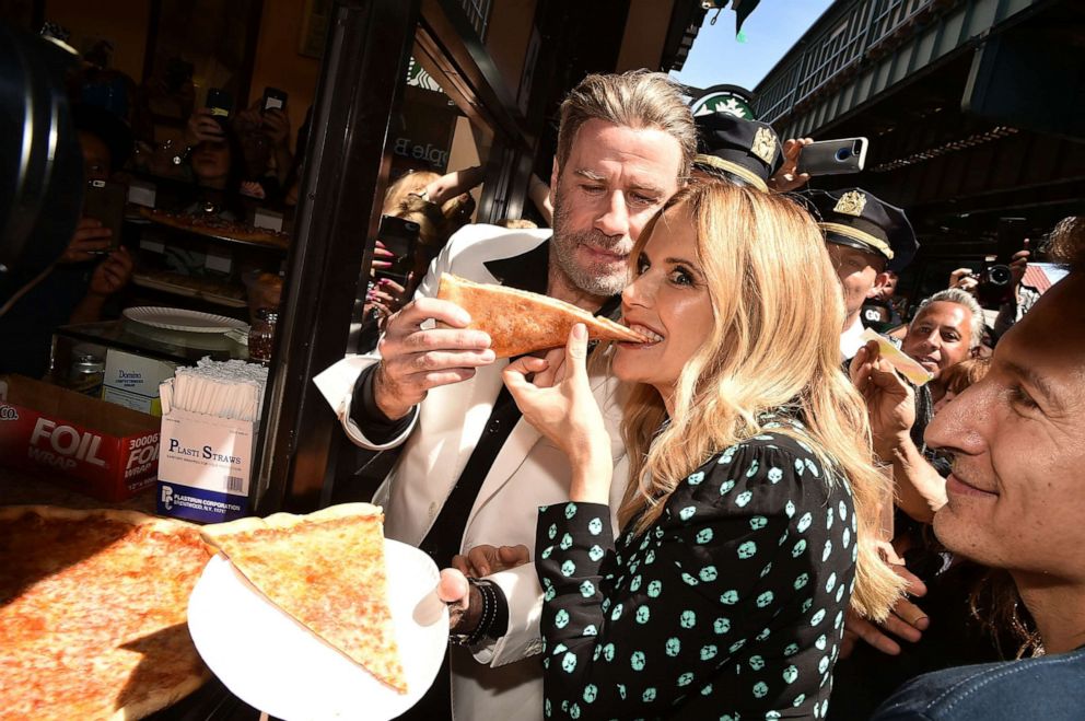 PHOTO: John Travolta and Kelly Preston eat pizza at a ceremony to honor John Travolta for his body of work in TV and Film, in anticipation of the release of the film "Gotti," June 12, 2018, in Brooklyn, New York.