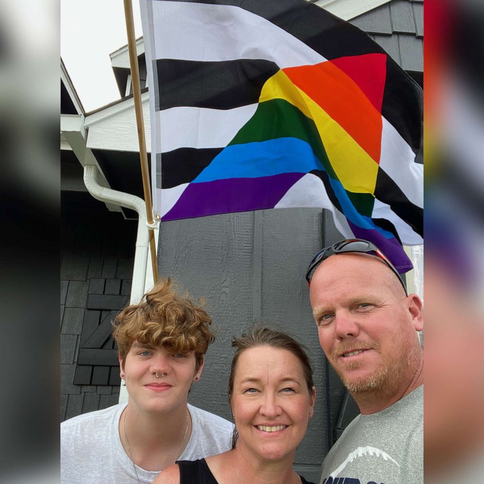 PHOTO: Caden, Janell, and John Wyatt pose for a photo with the pride flag in front of their home in Owasso, Okla., on June 5, 2021.