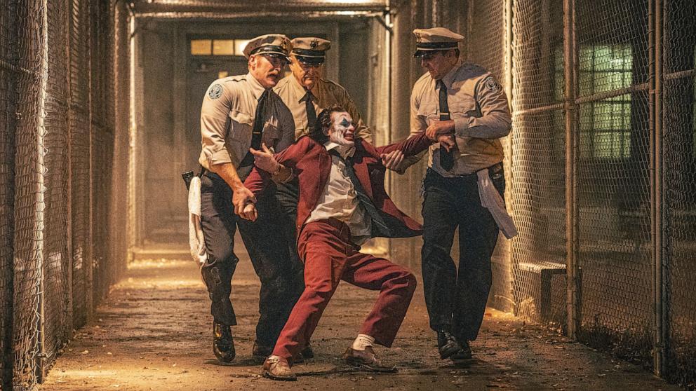 PHOTO: This image released by Warner Bros. Pictures shows Joaquin Phoenix, foreground center, and Brendan Gleeson, background center, in a scene from "Joker: Folie Ã  Deux." 