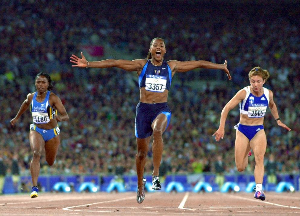 PHOTO: TMarion Jones of the US (3357) exults as she crosses the finish line to win the final of the women's 100m, Sept. 23, 2000, at the Sydney Olympic Games.