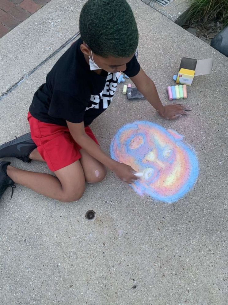 PHOTO: Josiah Wheeler, 11, draws an image in chalk of George Floyd.