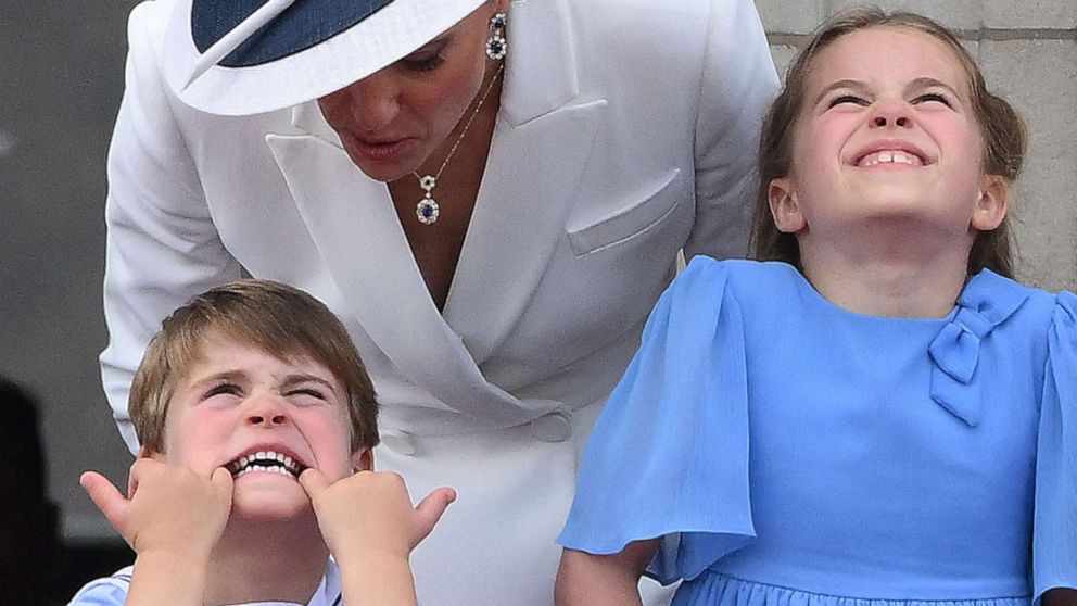 PHOTO: Catherine, Duchess of Cambridge talks to Prince Louis who is pulling a funny face, as they stand with Princess Charlotte of Cambridge to watch a special flypast from Buckingham Palace balcony in London on June 2, 2022.