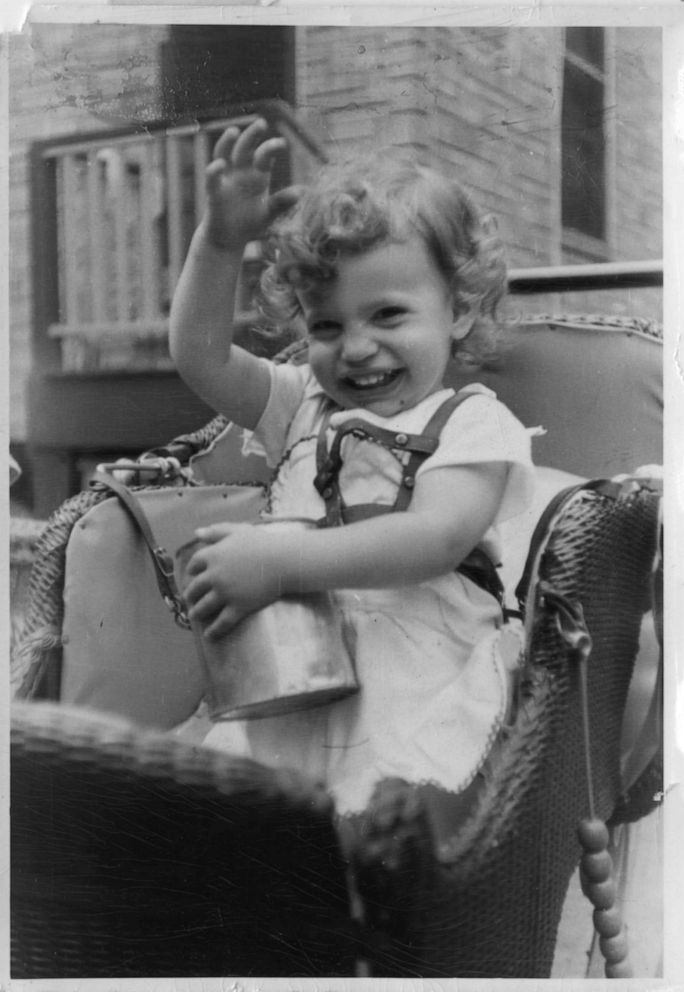PHOTO: An undated photo shows a young Judy Heumann waving to camera in a small carriage.