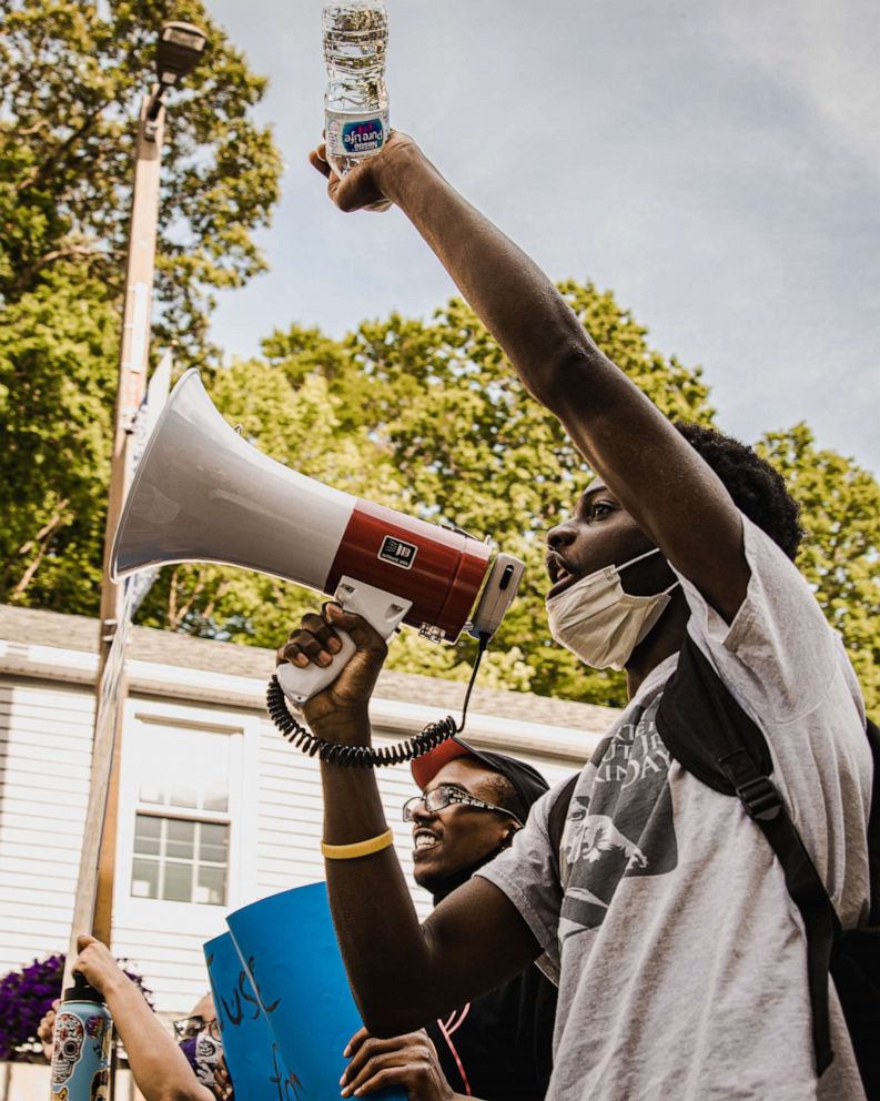 PHOTO: Junior Dufort raises his fist and yells through the microphone while marching through Norwich, Connecticut.