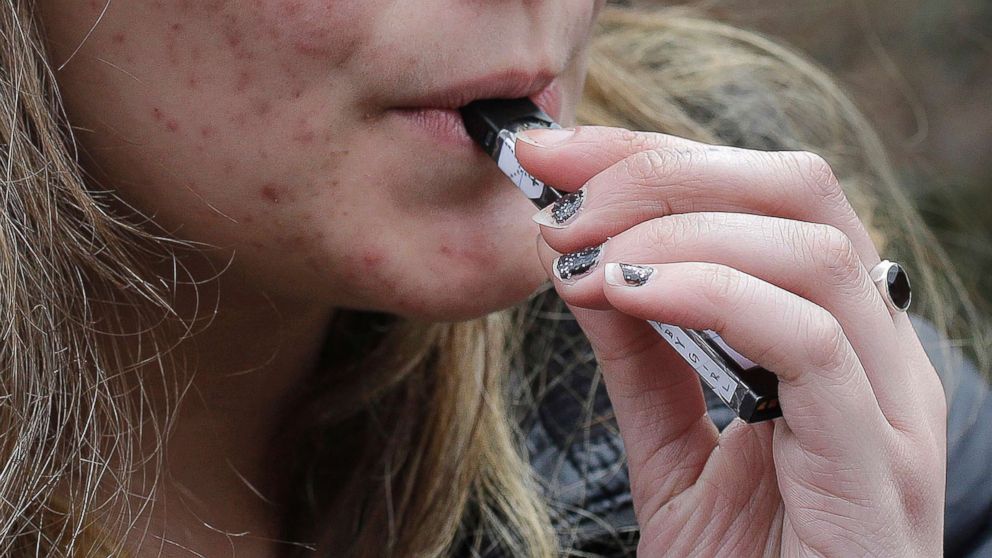 PHOTO: A high school student uses a vaping device near a school campus in Cambridge, Mass., April 11, 2018.